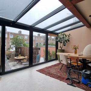 Serre met glazen dak en planten bij de woning door Select Kozijnen