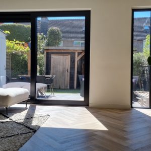 Interieur met zwarte deur en groot raam naar buiten door Select Kozijnen